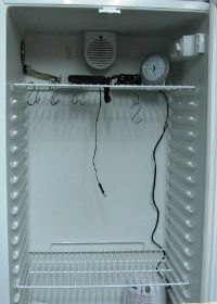 Wurstklimaschrank, die Würste sind gerade beim Räuchern, zu sehen sind obenlinks Lufteinlass, Klimasensor für die Regelung, schwarzer Umluftventilator, Hygrometer, unten ein Entfeuchter
